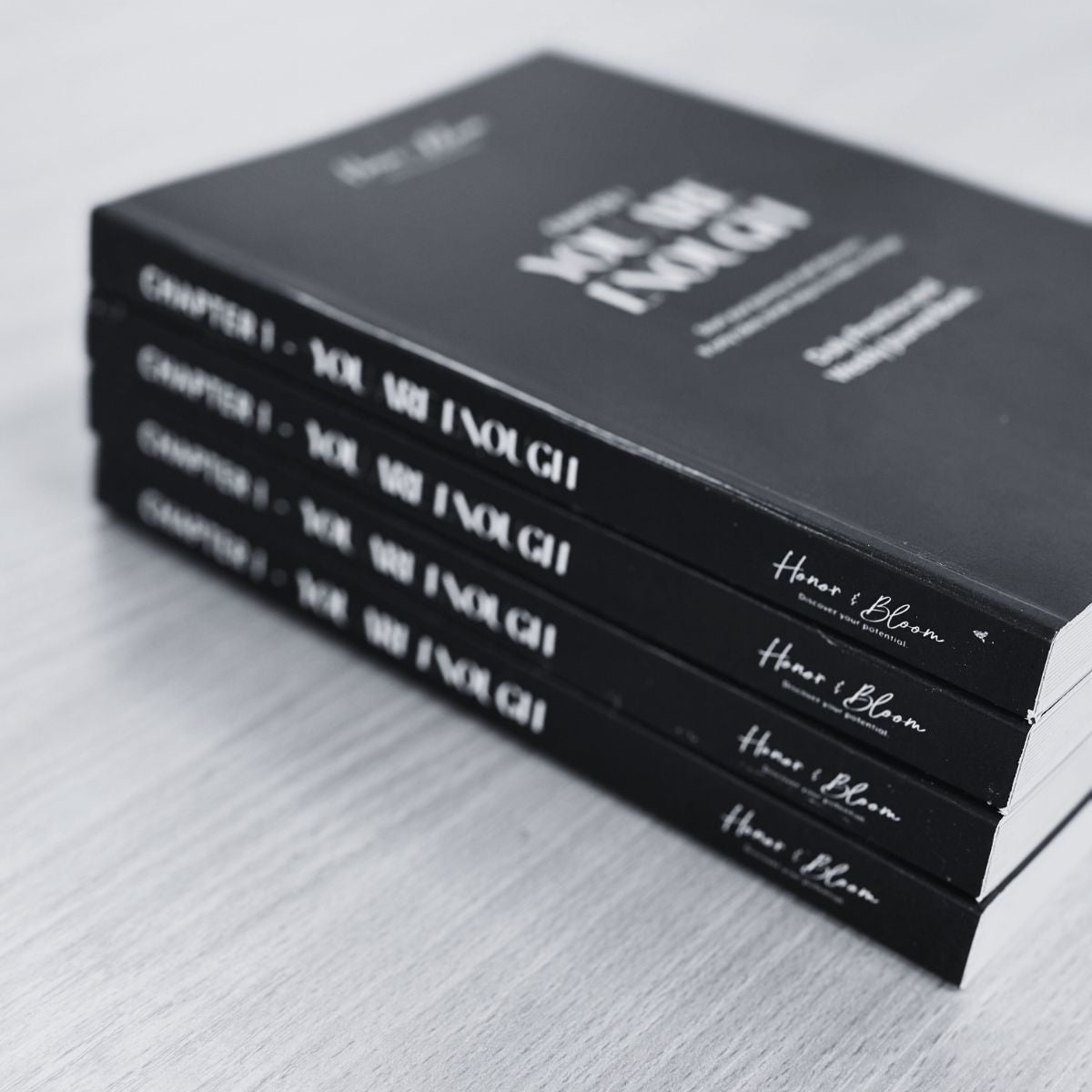 Stack of black books with white text on a light gray surface