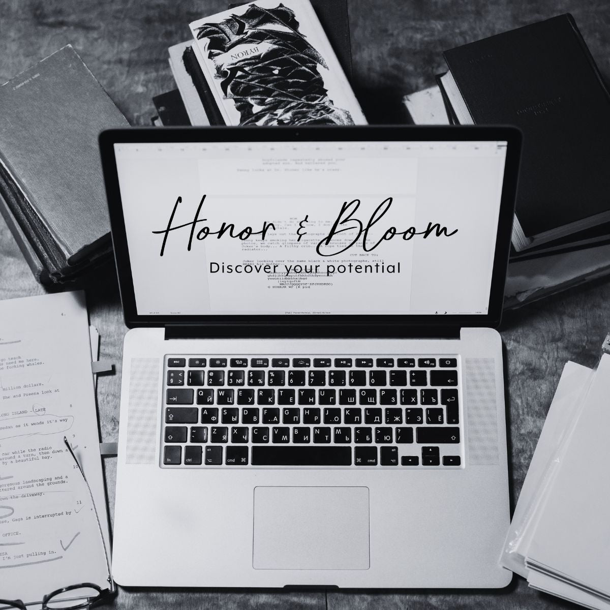 Laptop displaying 'Honor & Bloom' on a desk with books and papers.
