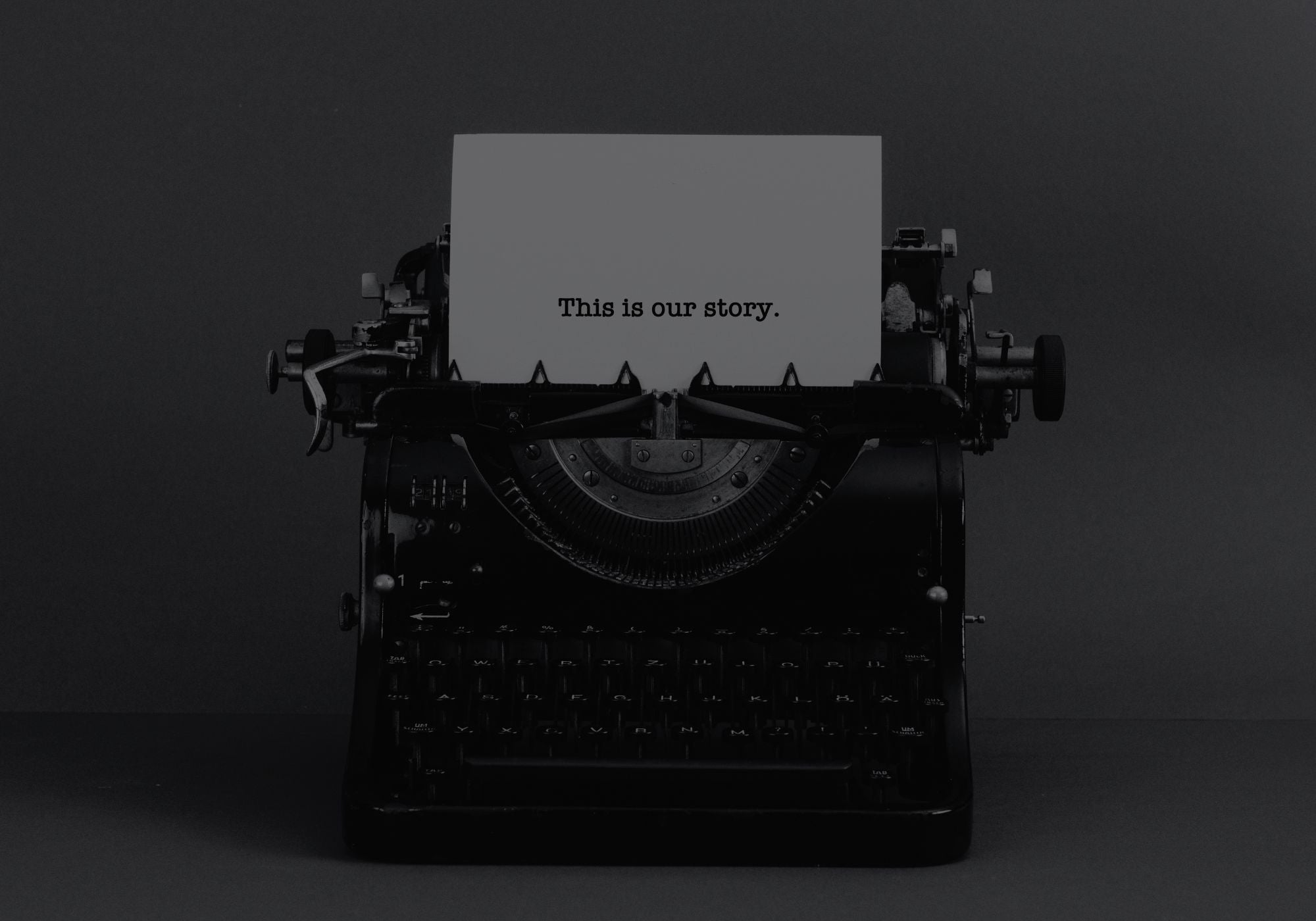 Vintage typewriter with a piece of paper displaying 'This is our story.' on a dark background