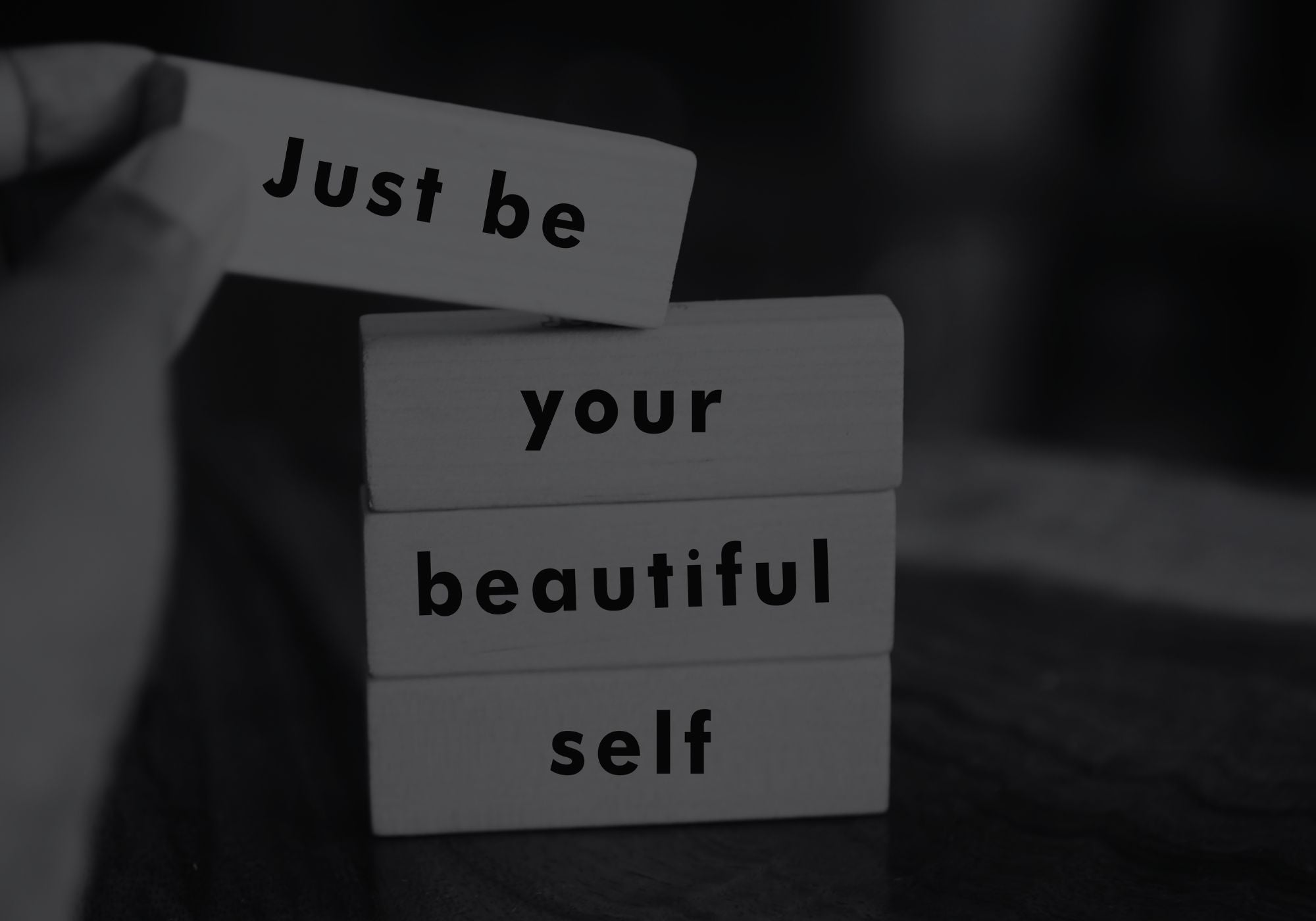 Stack of wooden blocks with motivational text 'Just be your beautiful self' on a blurred background