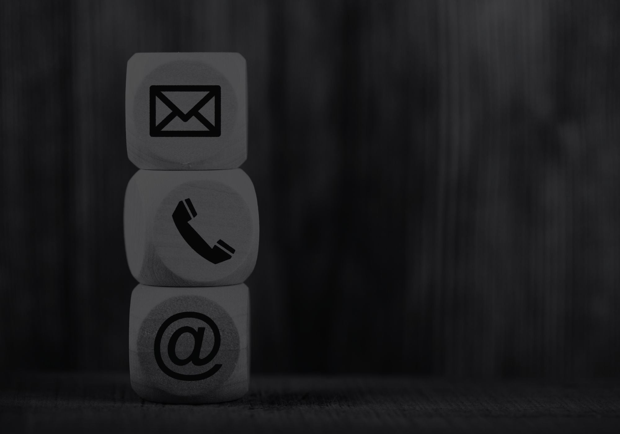 Three dice with contact symbol icons stacked on a dark background