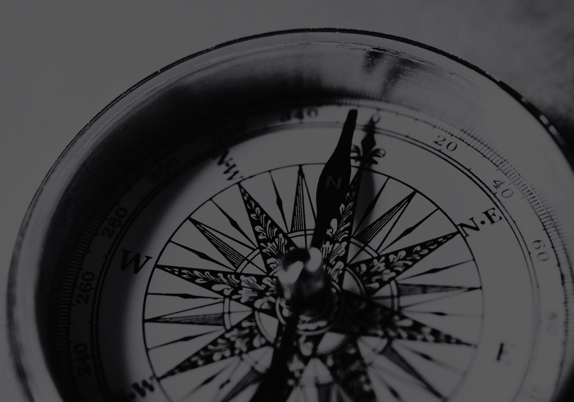 Black and white compass with decorative design on a dark background