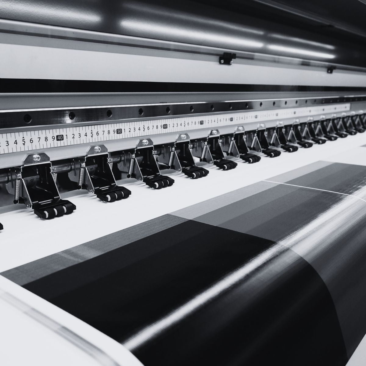 Large printing machine with a roll of black vinyl on a white background