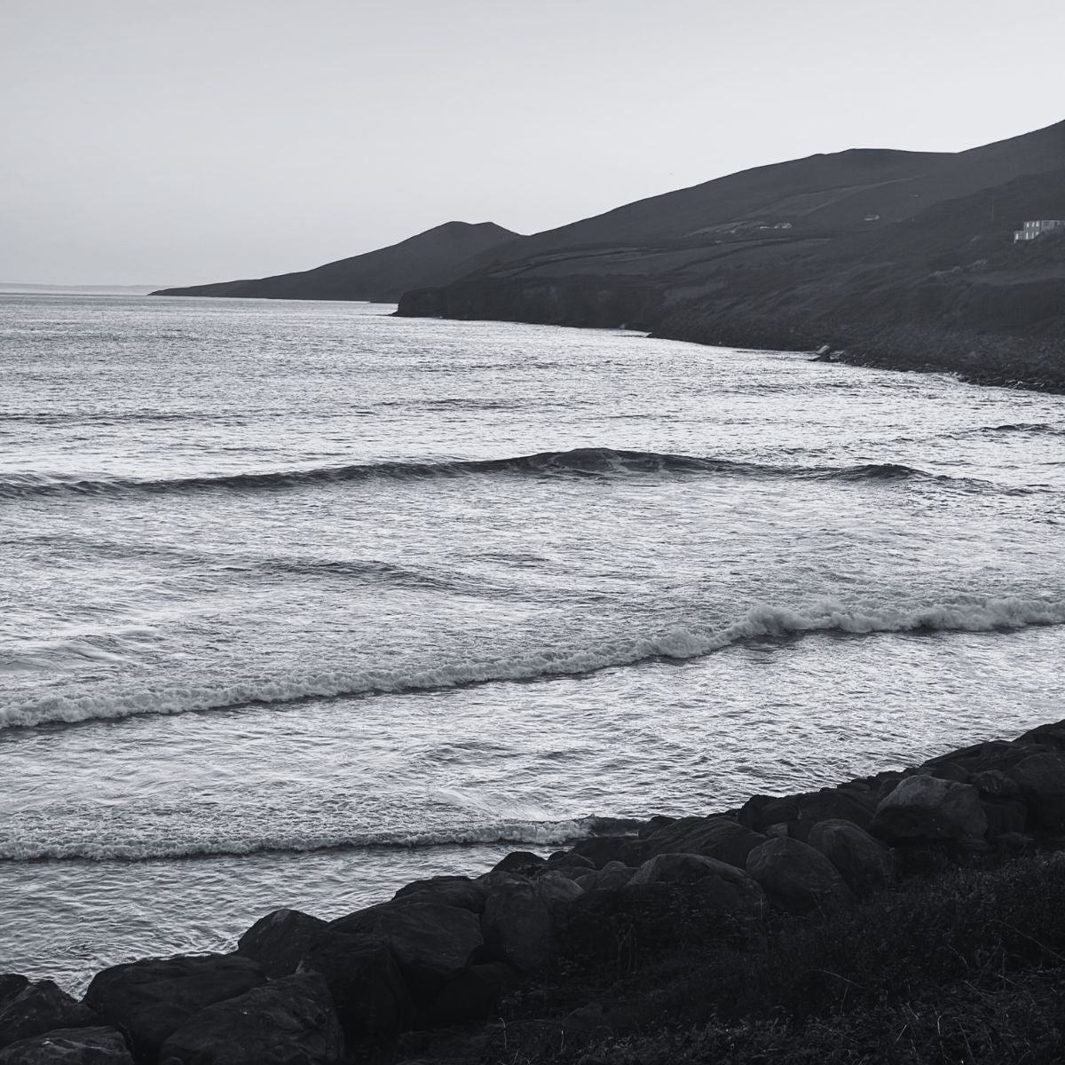 Black and white landscape of a coastal scene with waves and cliffs.