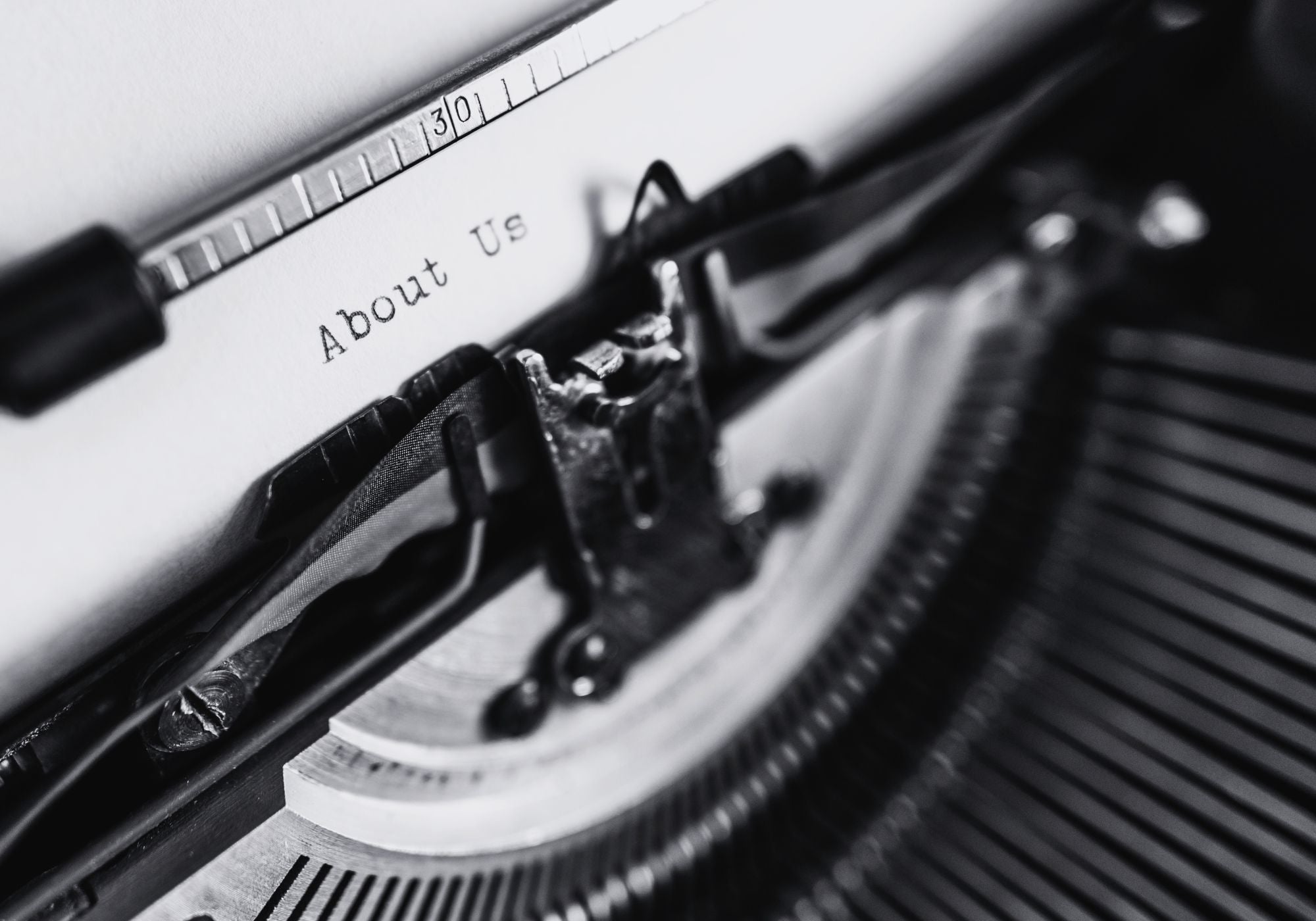 Close-up of a typewriter with 'About Us' text on a sheet of paper.