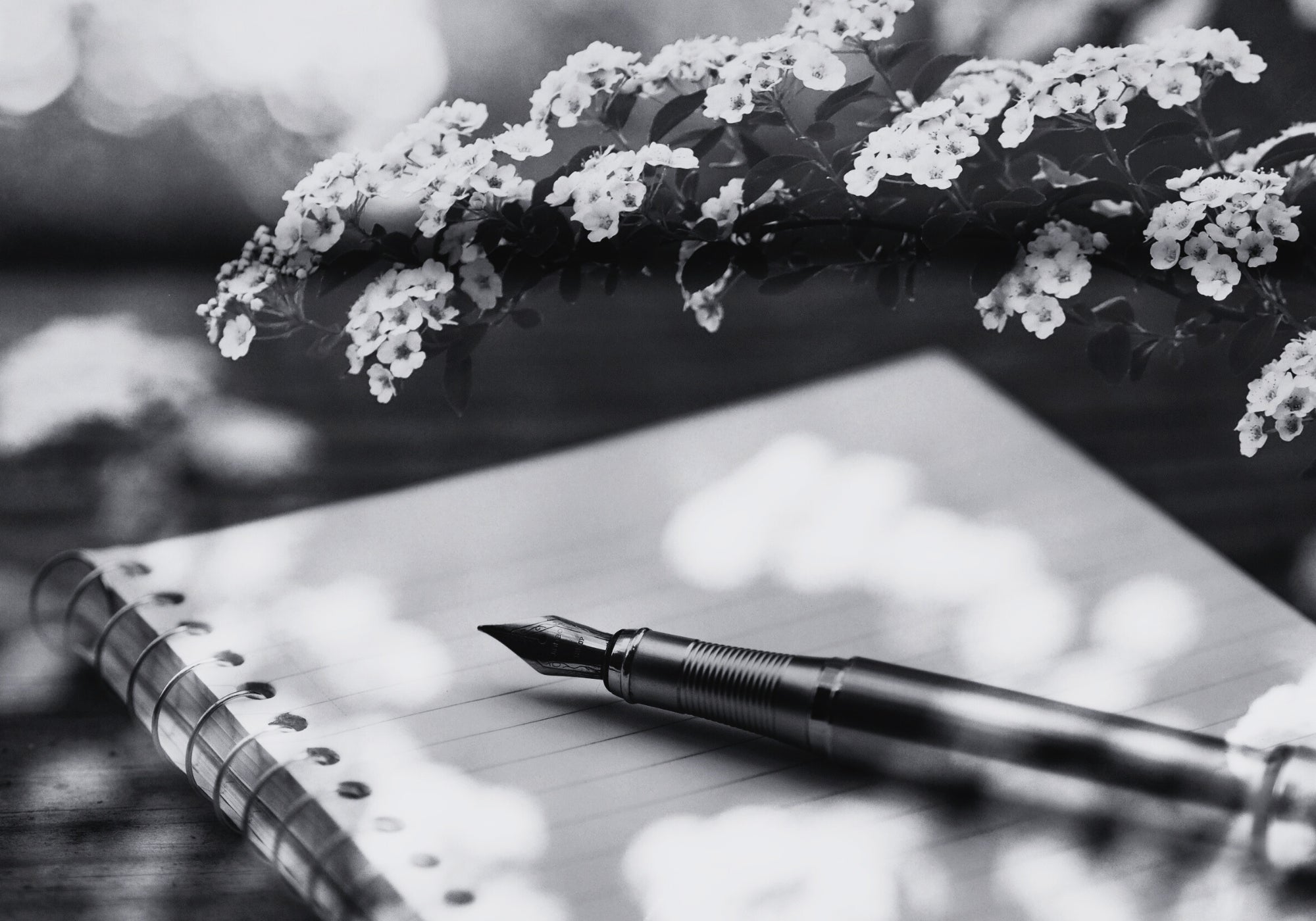 Notebook with a pen and flowers on a blurred natural background